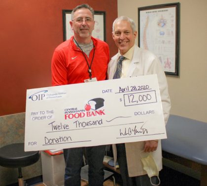 OIP's CEO William Thompson (left) and Dr. Raymond Lippe present check showing The OIP Foundation's $12K donation to Central Pennsylvania Food Bank for COVID-19 Crisis Response Boxes.